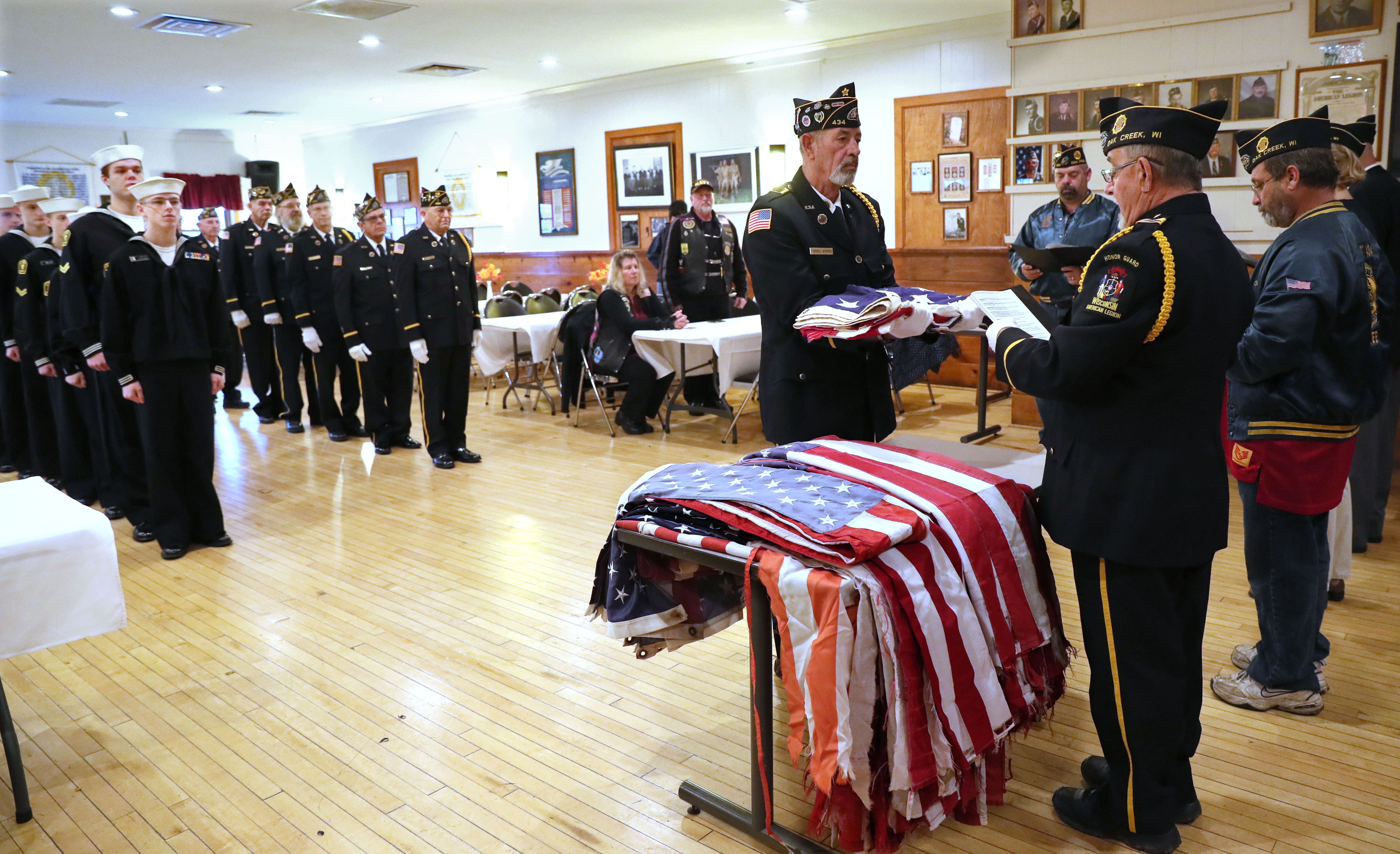 Darrell Wimmer a member of the honor guard, holds a flag as George Rainer (right), the honor guard commander, starts the ceremony to retire the flags to be retired. Members of the post, and a unit of United States Naval Sea Cadets ( a high school and middle school program) are in the background.

Photo by Michael Sears/Milwaukee Journal Sentinel